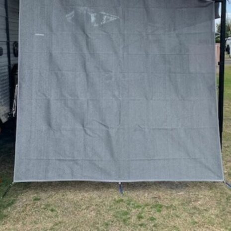 A Pop Top privacy screen end wall / side sun shade is being used as a privacy screen next to an RV.